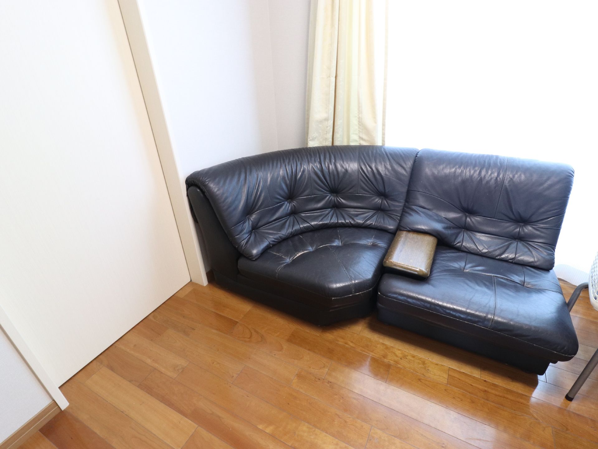 フローリングの部屋の窓際に、黒いコーナーソファが置かれている。ここで寛いだり、座って談笑したりすることができる。