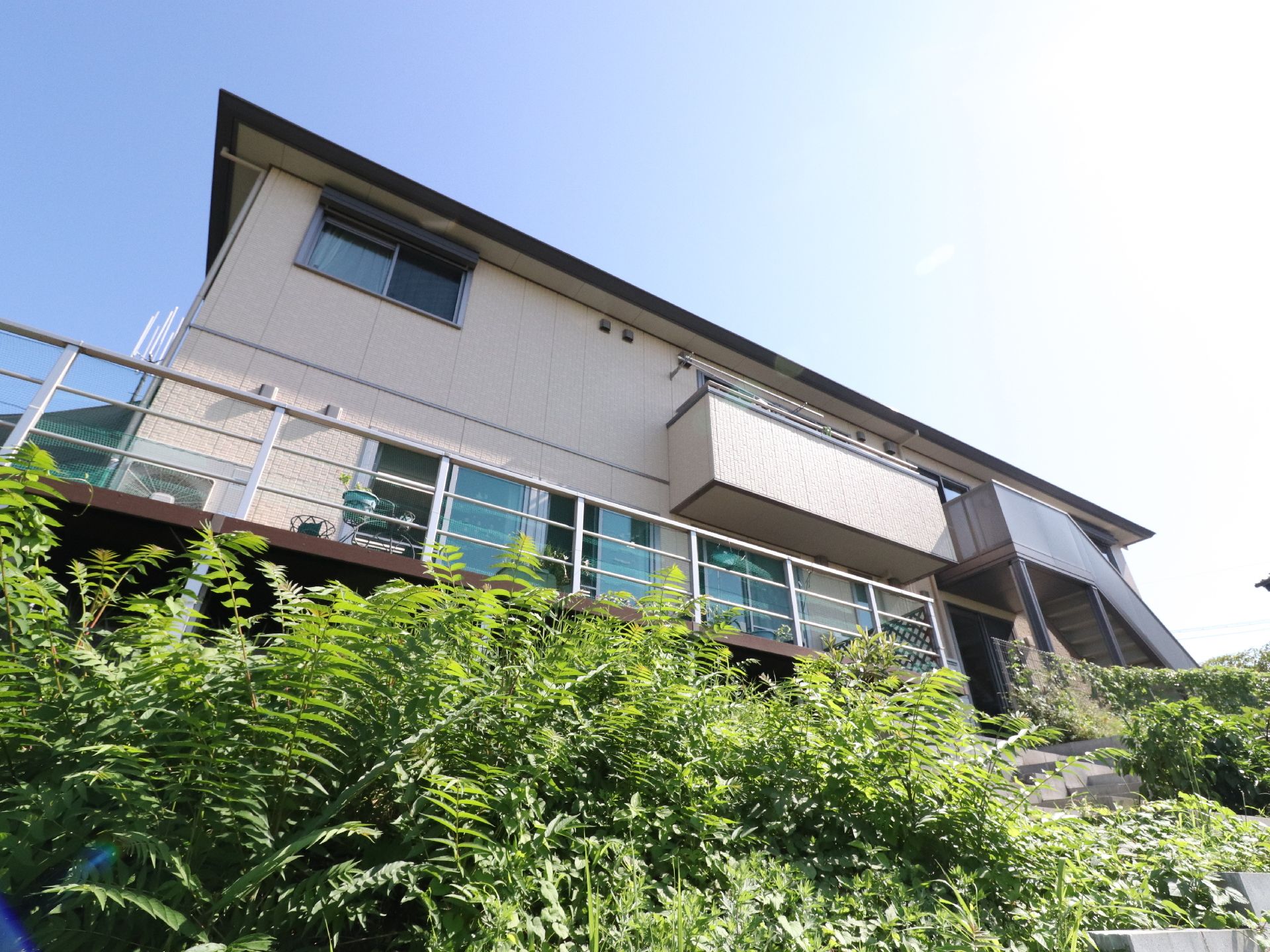 施設の建物は2階建てで、右側には外階段が設けられている。壁には窓が並んでおり、一部にはベランダが設置されている。