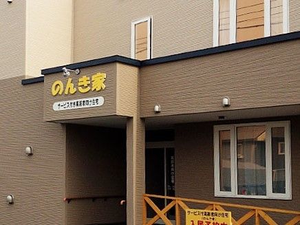 ブラウンとベージュの壁に、白い窓枠がおしゃれな建物。入口上のひさしには、大きく施設名が書かれている。