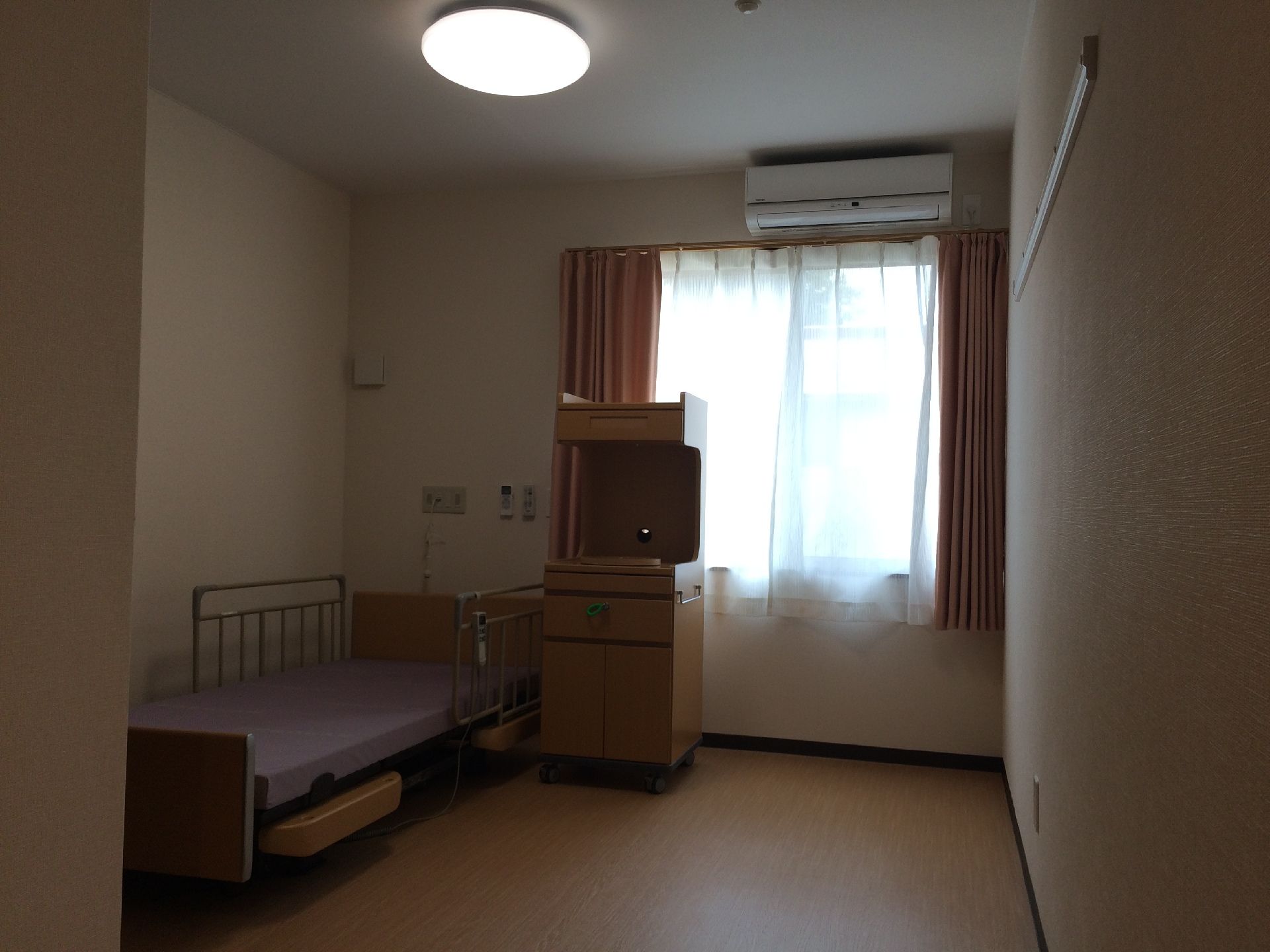 ベッドと収納棚、カーテンが取り付けられている使用されていない居室