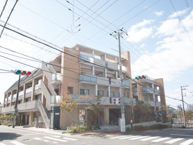 交差点の角にホームの建物が建っている。4階建てで、各部屋のベランダには陽が良く当たっている。非常用の外階段がついている。