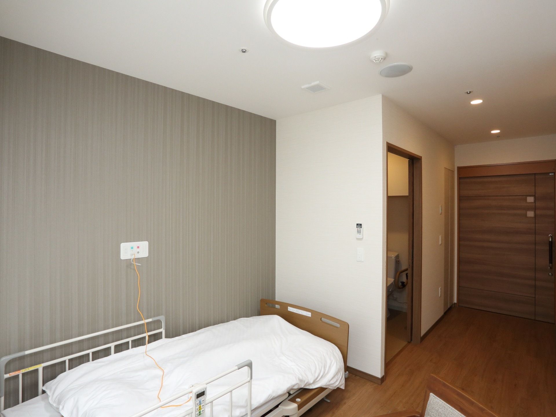 入口には木目調の大きな引き戸が設置されている。入口の横にはトイレがありドアが空いている。床面はフラットなので安心して移動できる。