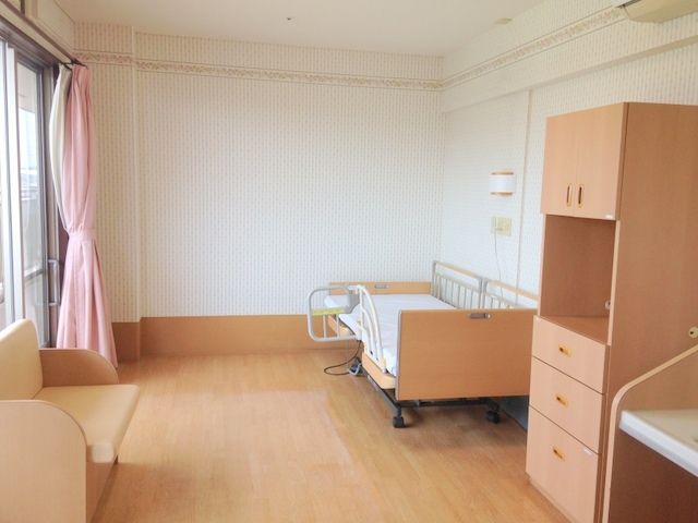明るい木目のベッド、収納家具、ベンチがあり洗面台付の居室