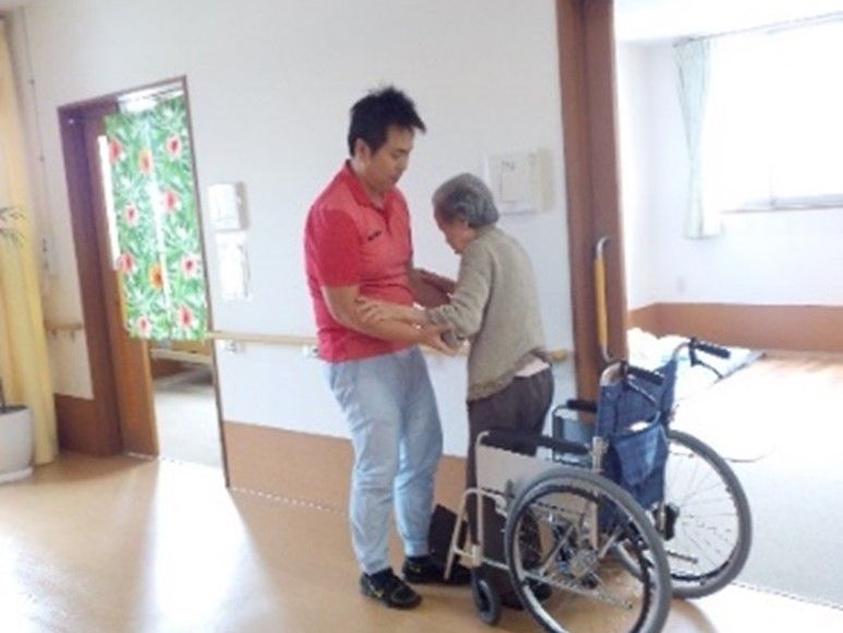 車椅子から立ち上がる入居者様をサポートしているスタッフ