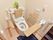 トイレに観葉植物が飾られている。便座の後ろ側に背もたれがある。便座の横だけでなく便座の正面にも可動式の手すりが設置されている。