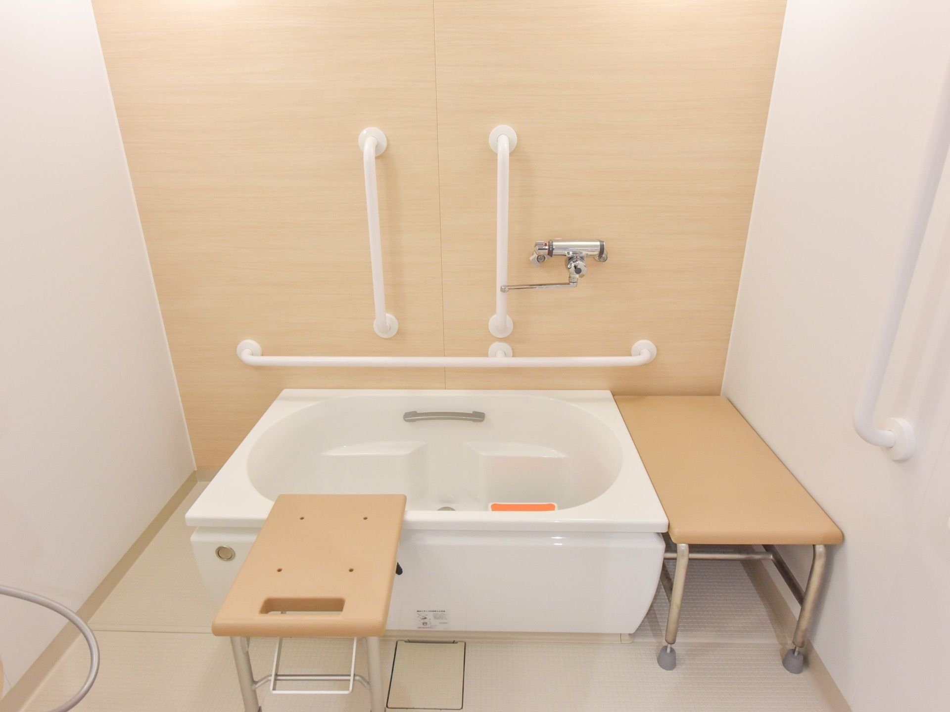 個浴用の浴室の一例。壁に手すりが設置されている。補助用の椅子が２種類用意されており、１脚は折り畳みが可能である。