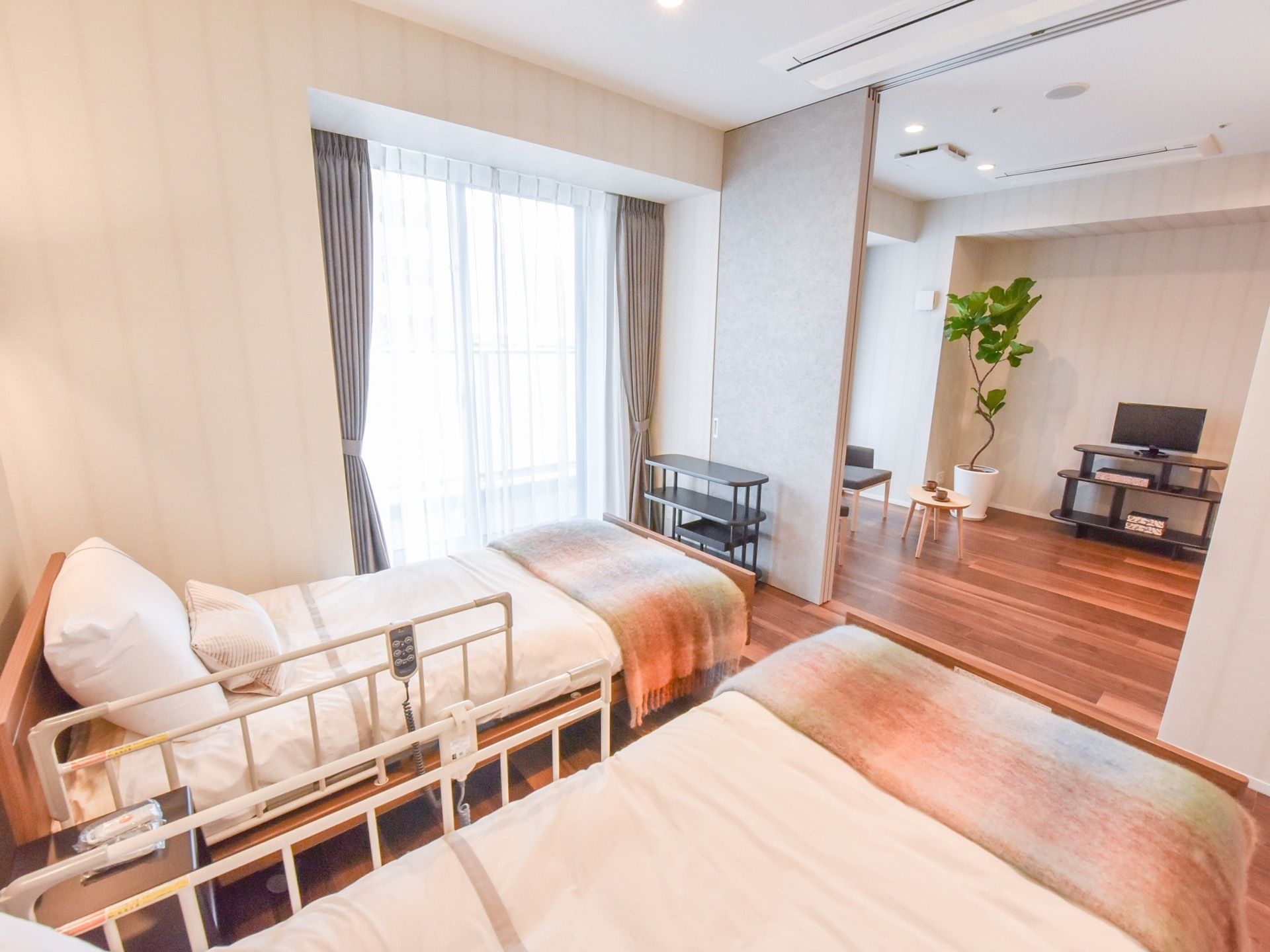 ２人部屋の一例。二間続きとなっており、リビングには大型液晶テレビが置かれている。テレビ横には鉢植えの観葉植物が飾られている。