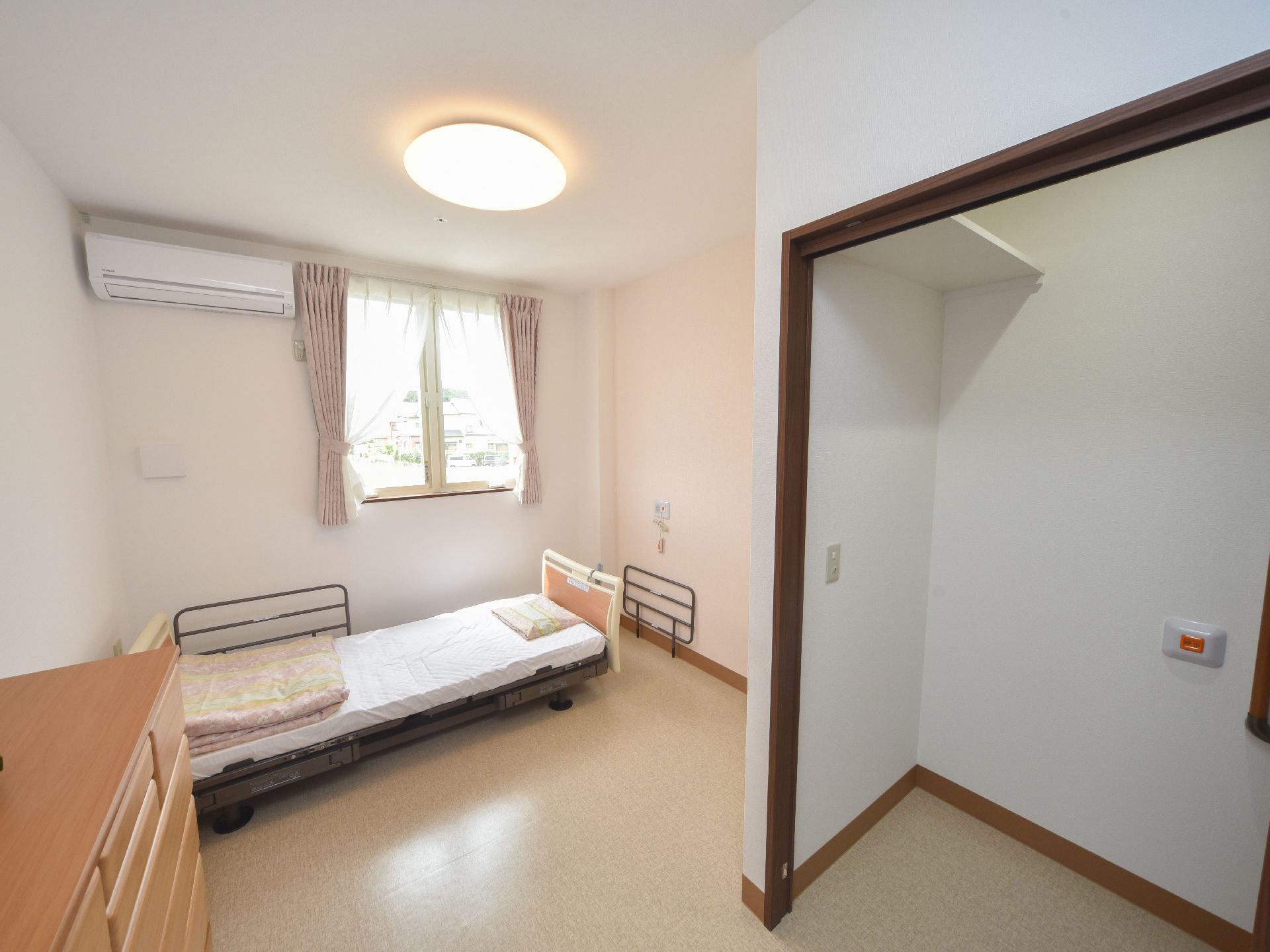 明るい内装の部屋で、ベッドとタンスが置いてある居室