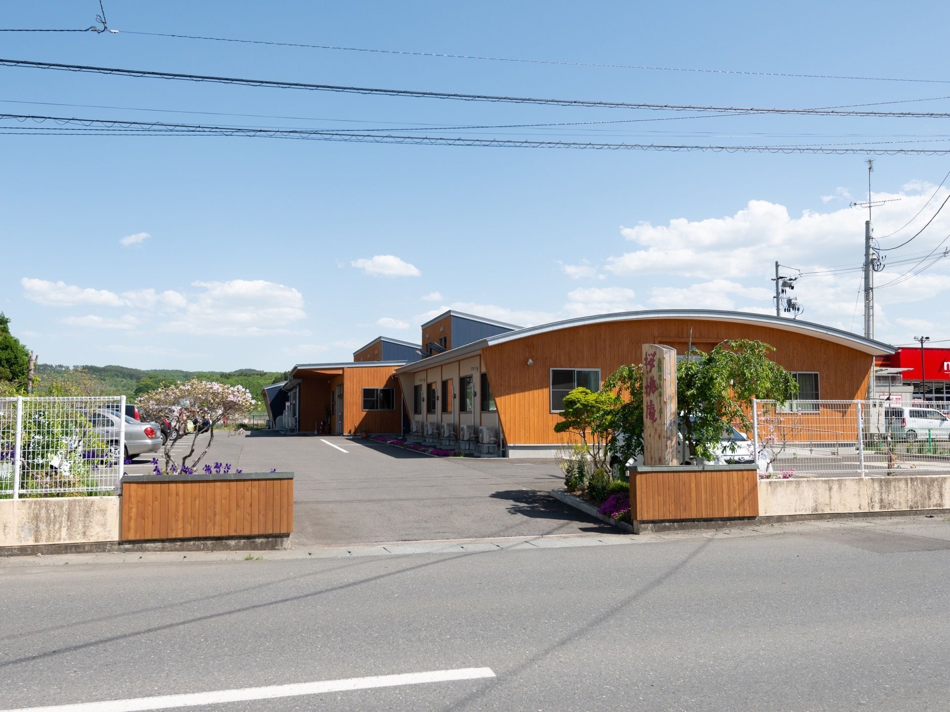 施設は木目が多く使われた落ち着いた雰囲気の建物である。敷地の車の出入り口には、さまざまな木々が植えられている。