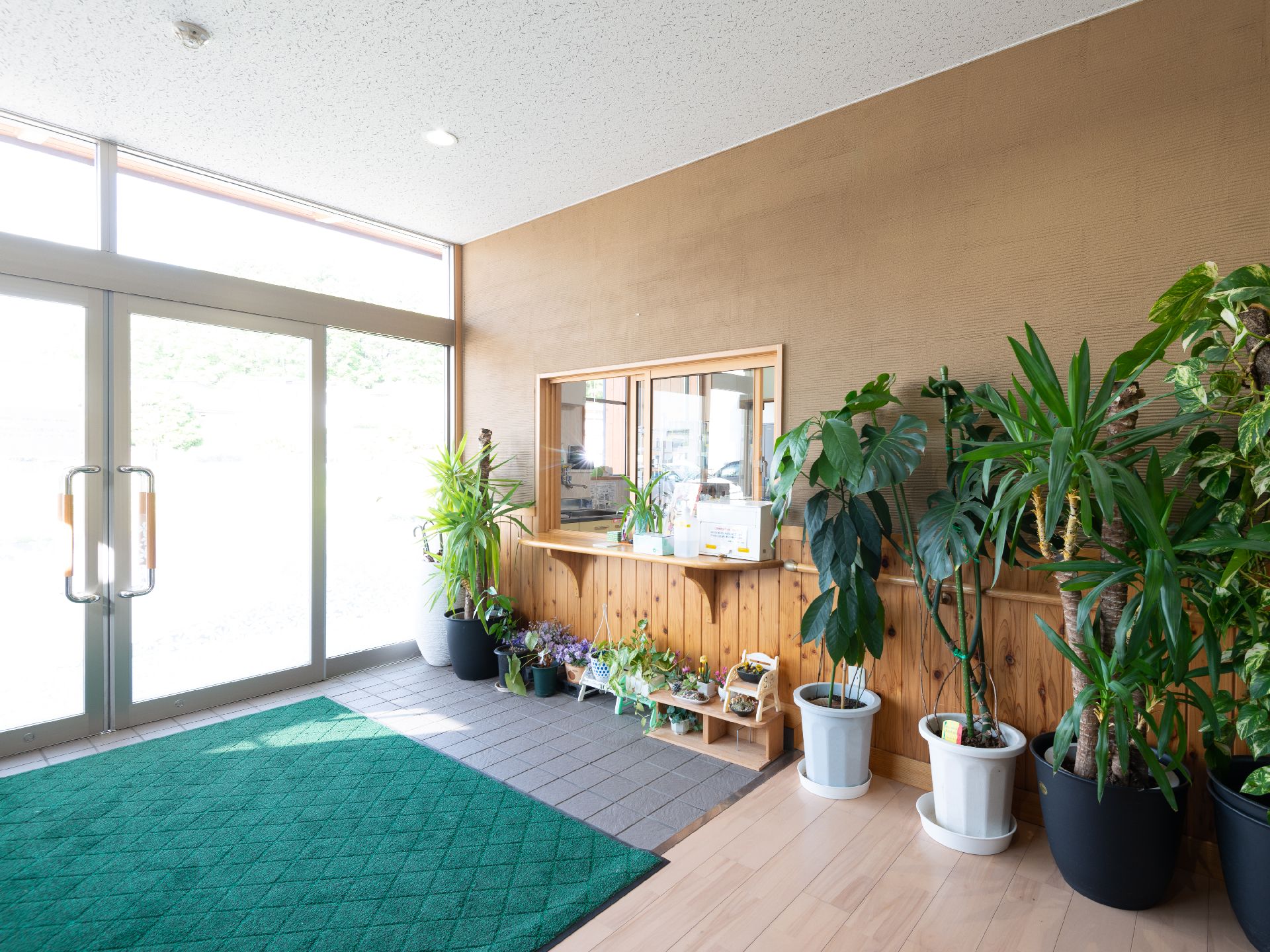 受付周りに花や観葉植物が複数並べられているエントランス