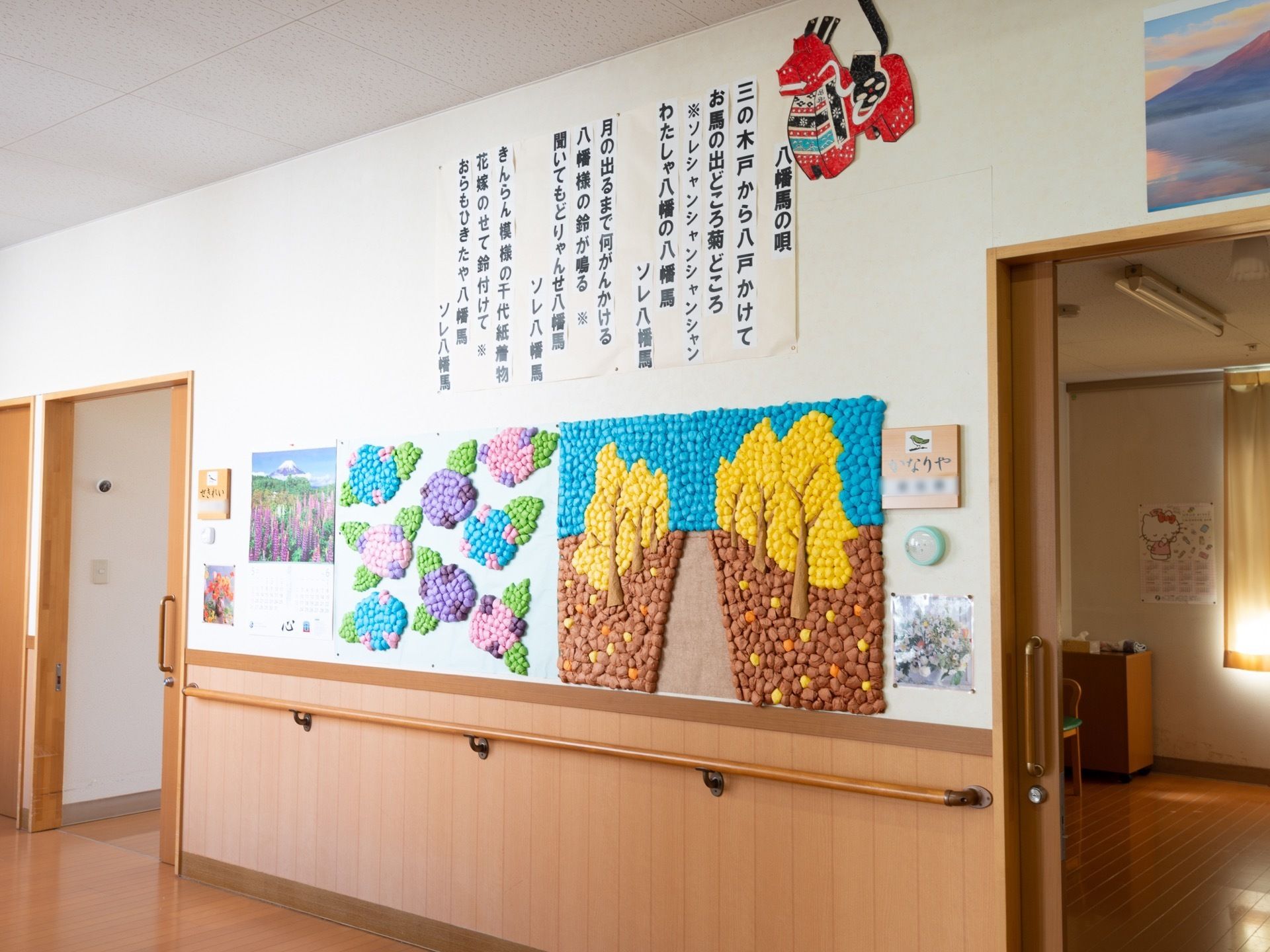 壁には手すりが備えつけられており、入居者様が製作した作品がレイアウトされている。各部屋のドアはスライド式である。