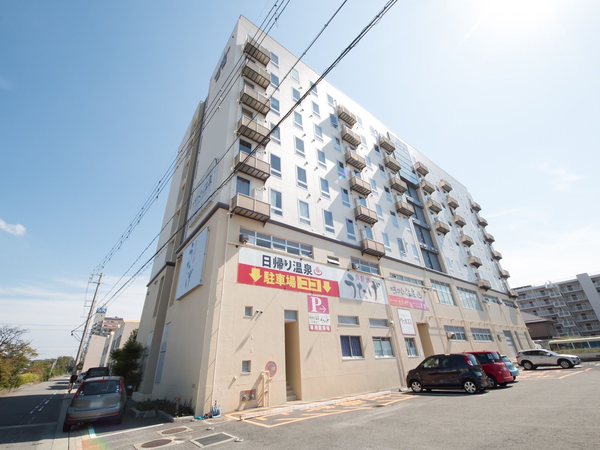 シンプルな四角形の建物である。広々とした駐車場を完備している。まわりの外観になじむ、やさしい色合いが印象的である。