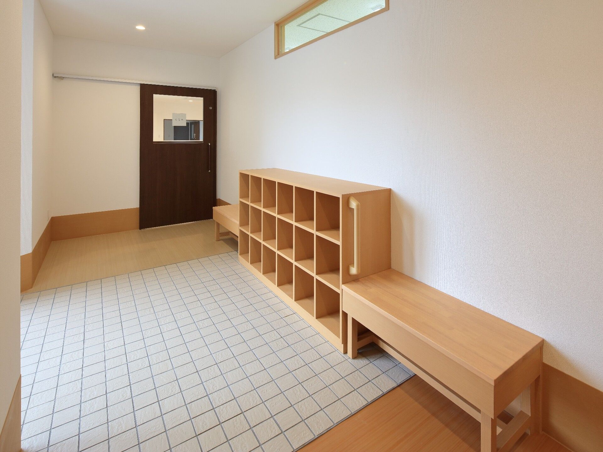 黒いレンガ調の壁に白い文字で施設名が書かれている。出入口のガラスの引き戸の扉には入居者募集の貼り紙がある。