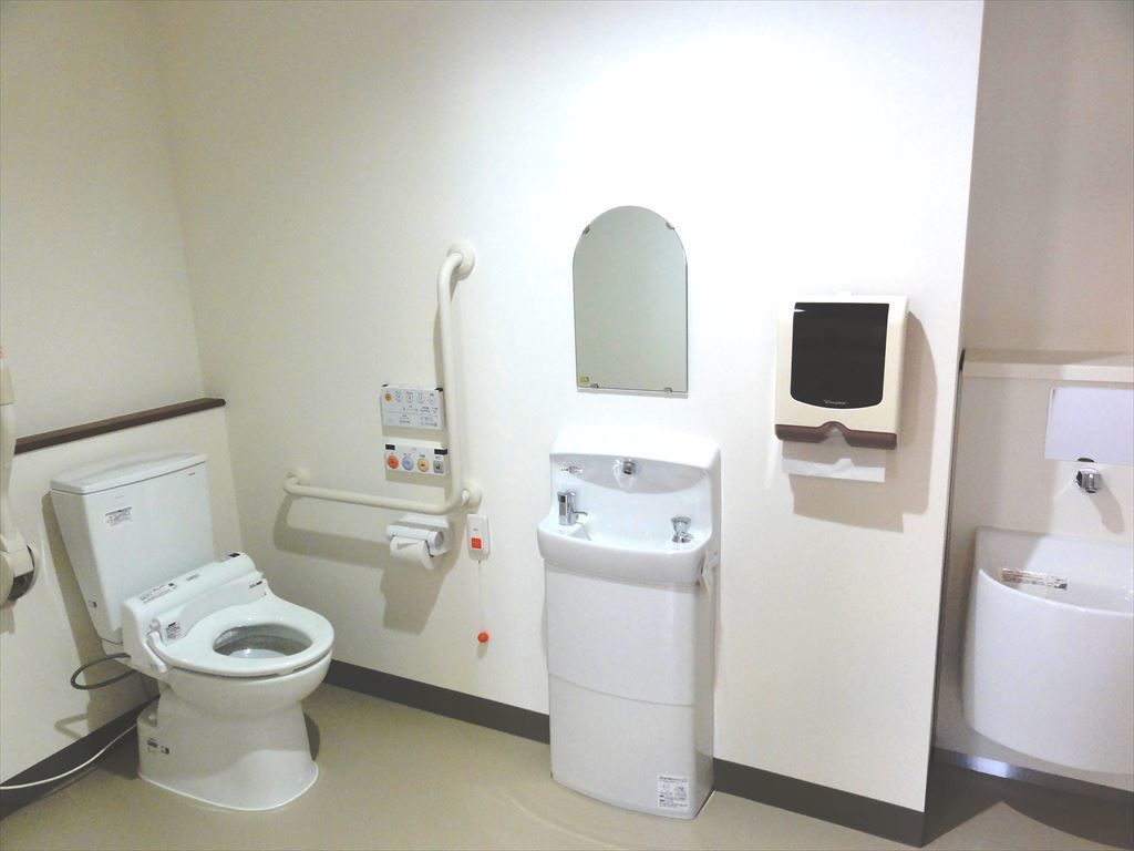 トイレ、手洗い場、鏡のある共用トイレ。どなたでもご利用いただきやすいように、手すりが完備されている。