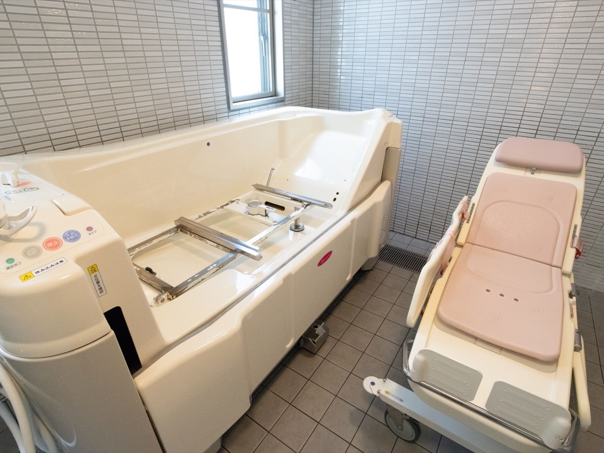 機械浴室には、専用ストレッチャーが備わった介護浴槽を設置されている。床や壁はタイル張りになっており、窓が設けられている。