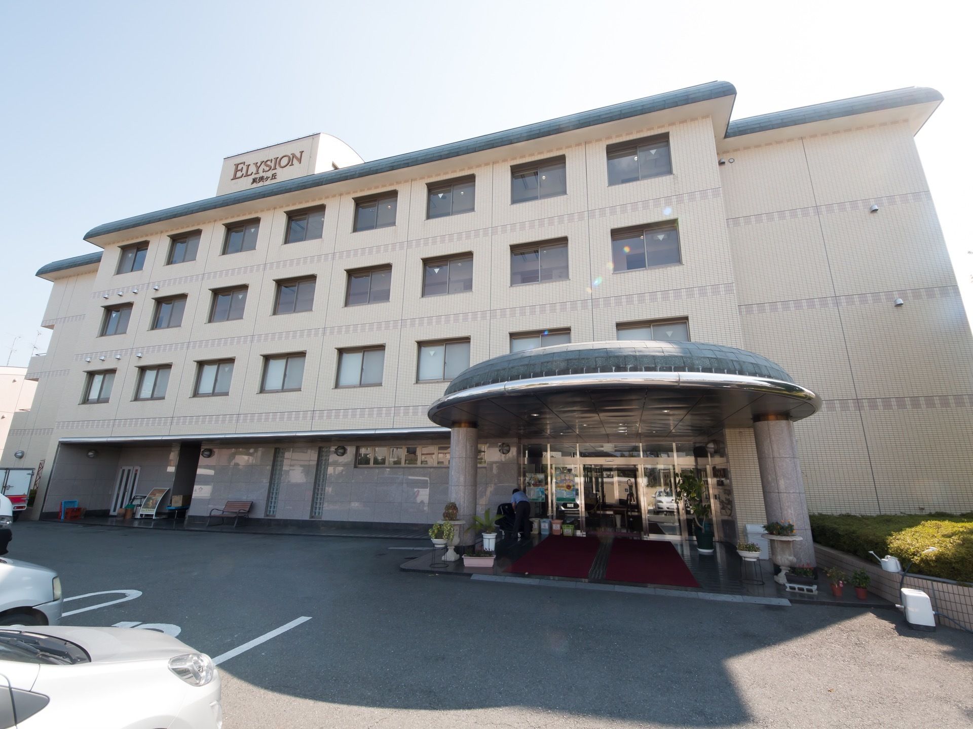 丸い印象の４階建てで、壁はクリーム色に塗られている。手前には駐車場がある。入口には屋根があり点字ブロックの両側に赤いマットが敷いてある。