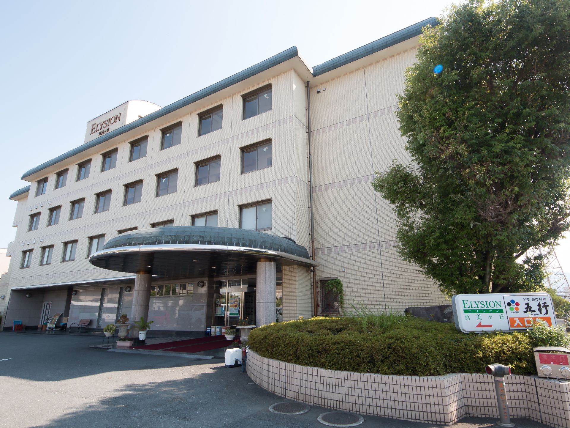 シンボルツリーがそびえたつ、玄関に大きな庇がある建物