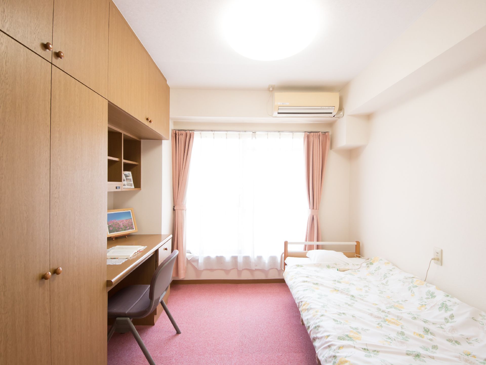 デスク付きの壁面収納とベッドがある日当たりの良い居室