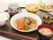 半円型のお盆の上に食事と箸が配膳されている。ご飯、お麩の味噌汁、野菜を使ったおかず、フルーツが用意されている。