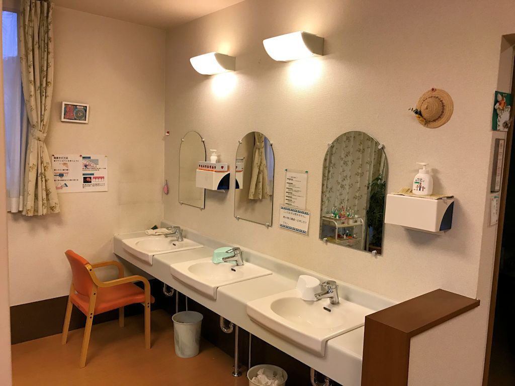 横並びに三つ設けられている、照明で明るい鏡付きの洗面台
