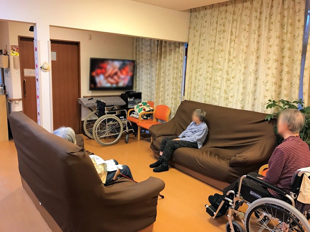 共有スペースには、壁掛けのテレビを設置している。背もたれの高い茶色のソファを設置しているので、ゆったりとくつろいでいただける。