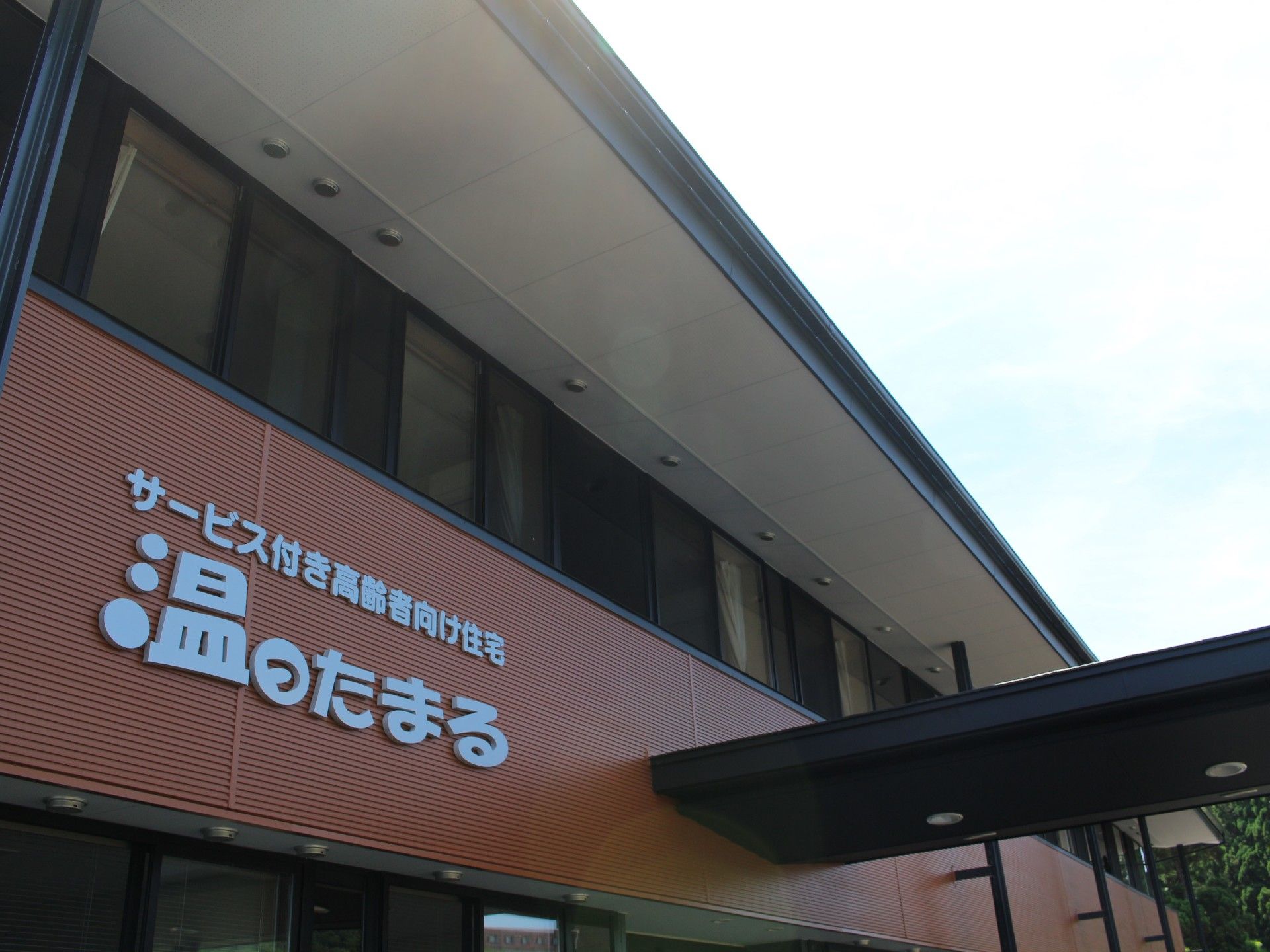 落ち着いた色の外壁に、大きく施設名が書かれている建物正面