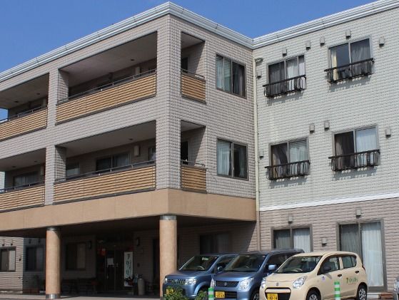 ３階建てのグループホームである。ガラス張りの自動ドアが設置された屋根付きの玄関で、建物の前には駐車場が設けられている。