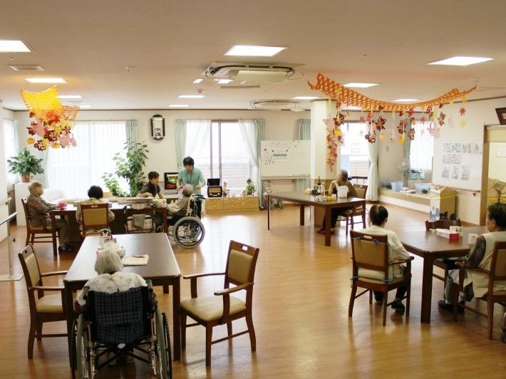 天井に飾り付けがされたリビングで、それぞれテーブルに向かって座る入居者様たち
