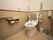 背もたれと手すりが設置されたトイレである。壁には緊急時呼び出しボタンや、水を流すためのボタンが備えてある。