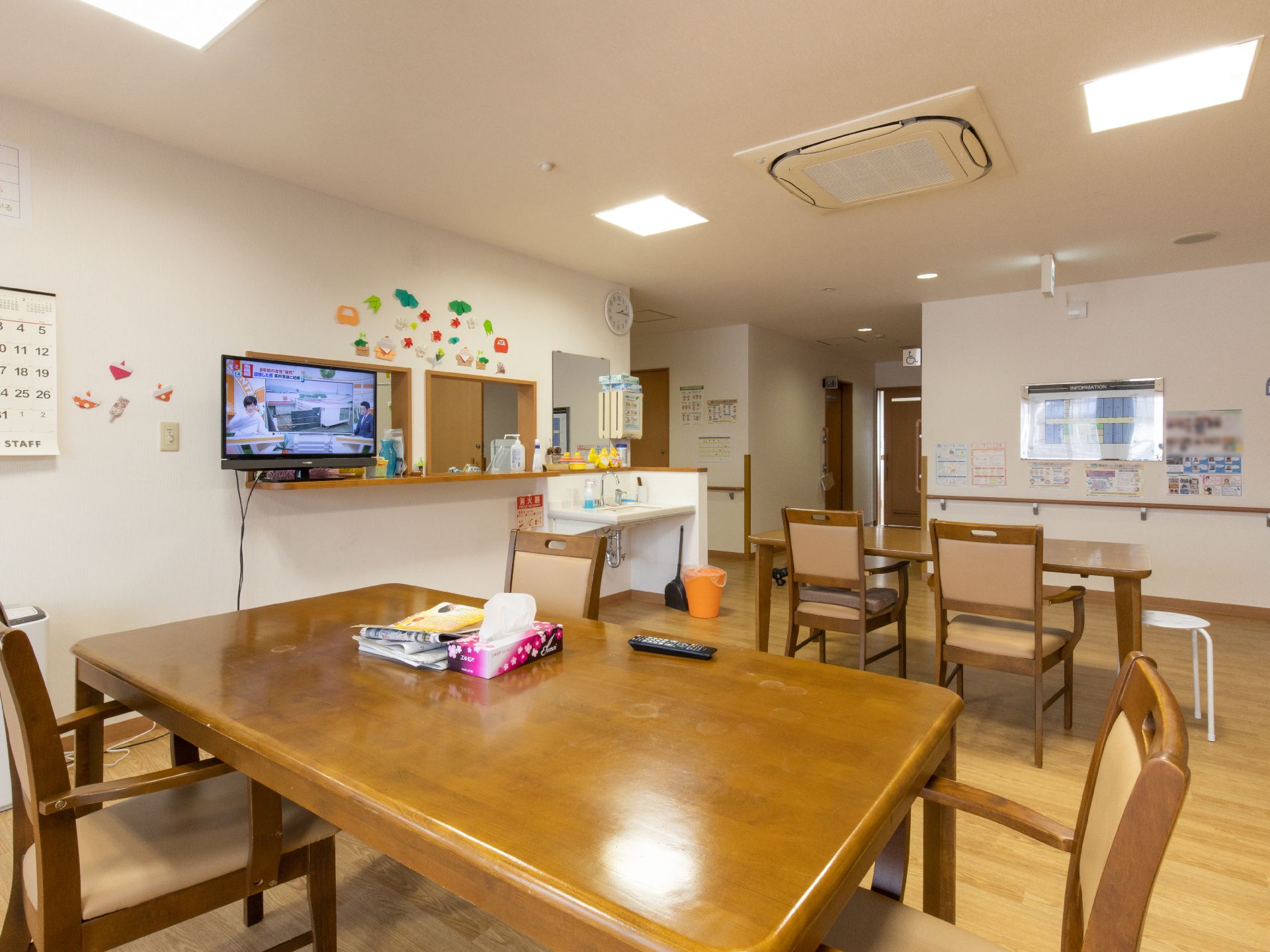 フローリングの食堂にはテーブルセットが２台置かれている。カウンターにはテレビが置かれ、隣には手洗い場がある。