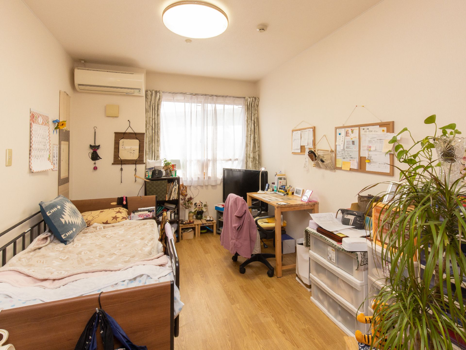 居室には介護ベッドやテーブル、洋服タンスなどが設置されている。テレビやエアコンなどの家電も置かれている。