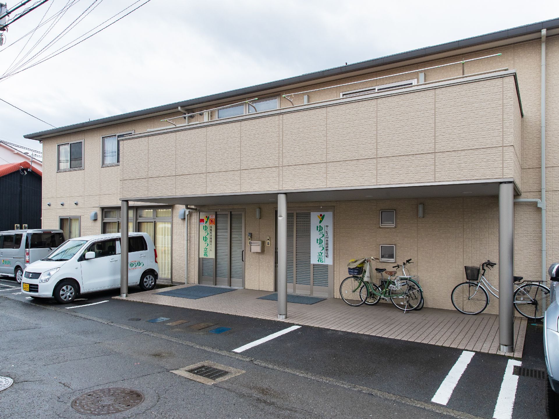 ２階のベランダが玄関前の大きなひさしになっている施設外観