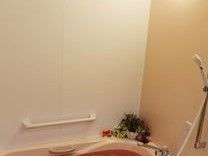 介助用の手すりやシャワーが備えられた優しい色使いの浴室。花が飾られ、スタッフの優しい心遣いが現れている。