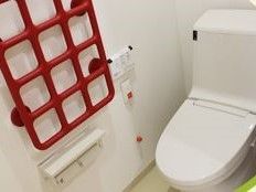 赤色で格子状の手すりが呼び出しボタンの横に設置されているトイレ