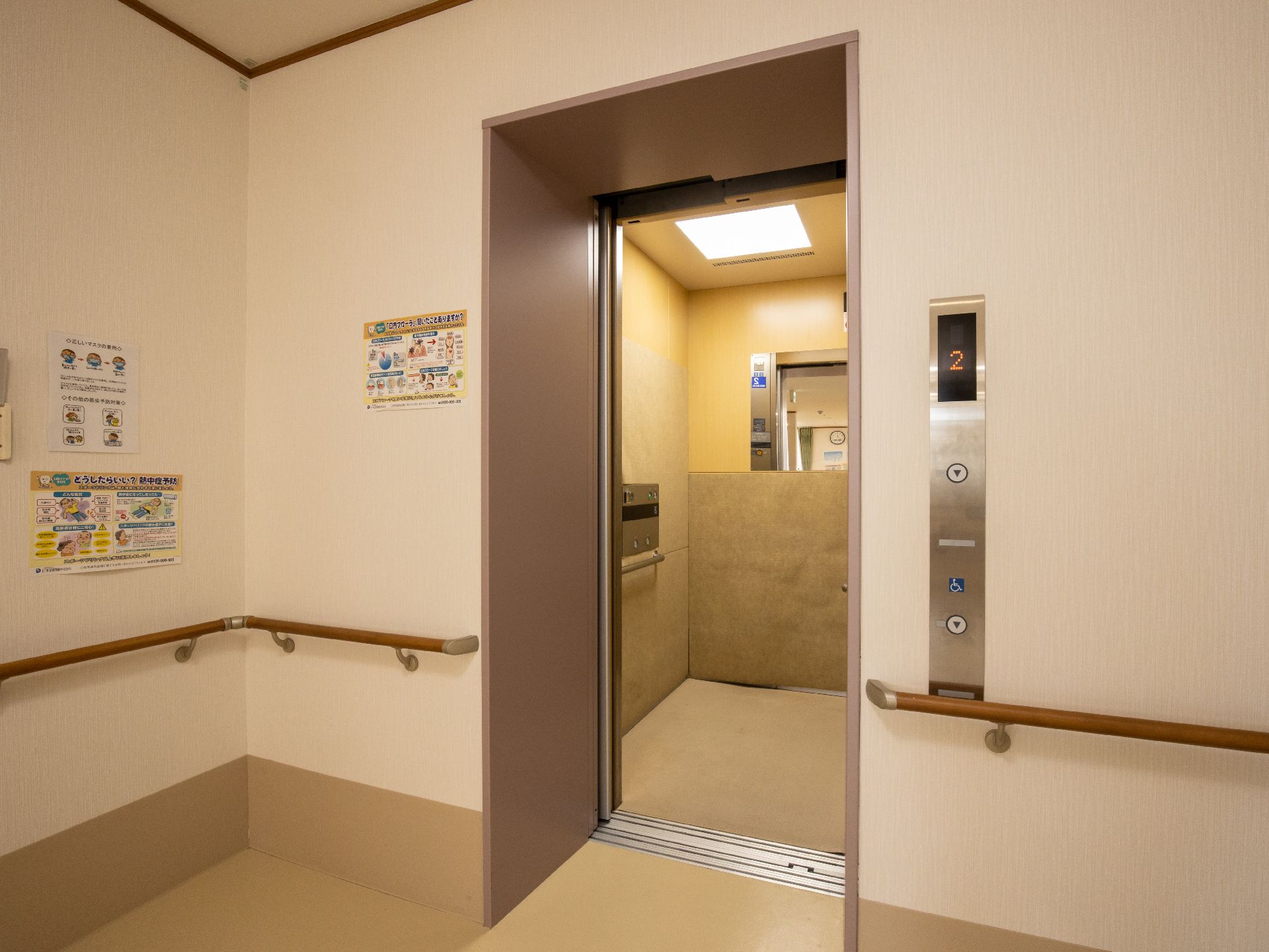 居室の入口ドアの前に大きなクローゼットがあり、折れ戸式の扉が閉まっている。その手前に白いチェストが置かれている。