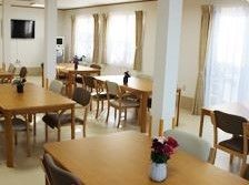 大きな窓がいくつもあり、壁掛けテレビが設置されている食堂
