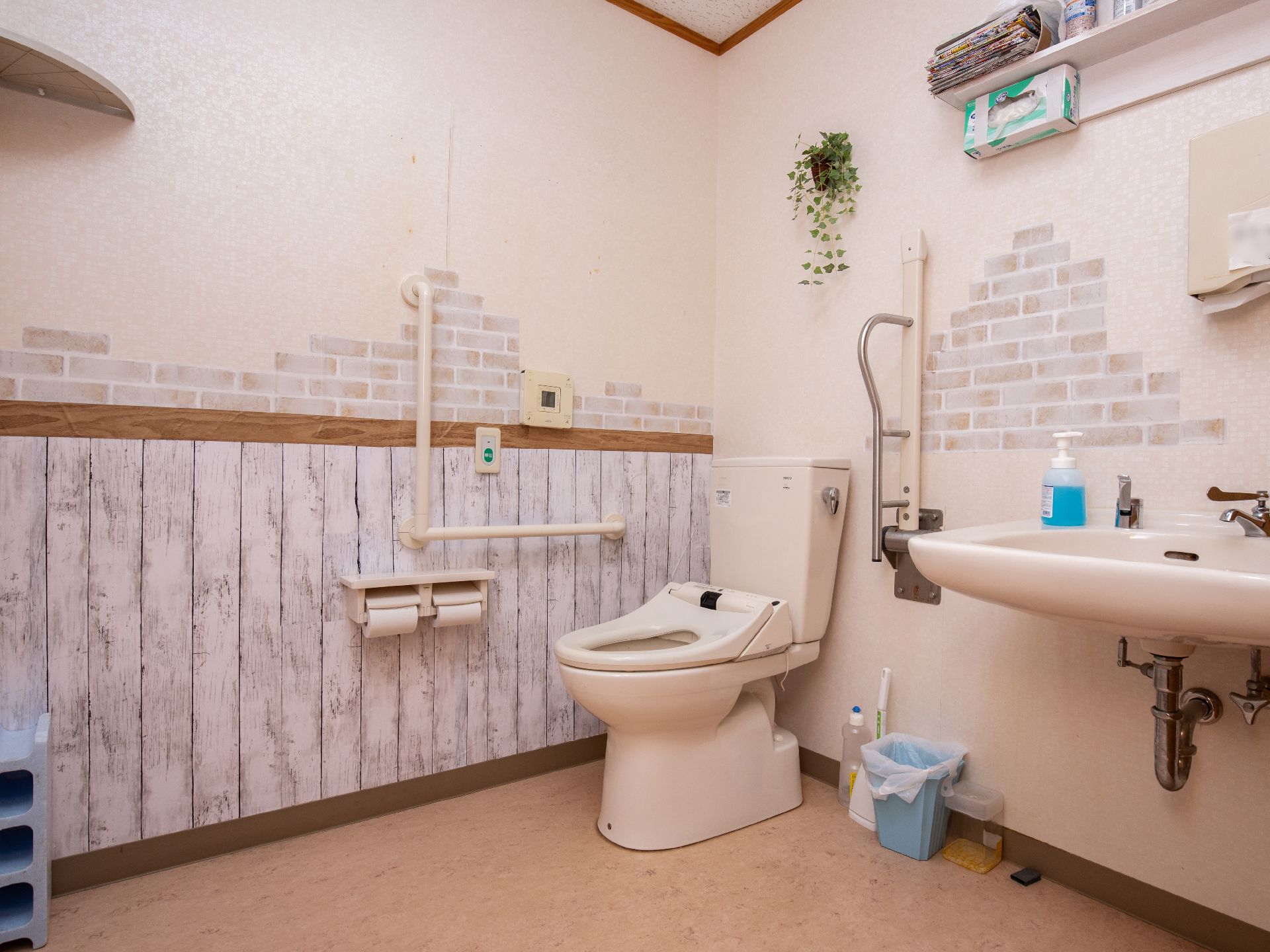 カフェ風のおしゃれな内装で、清潔感のあるトイレである。手すりを設けることで、立ち座りの動作による負担を軽減している。