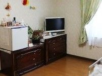 濃い茶色の収納棚が並べて置かれ、その上にテレビが載っている居室の壁際