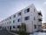 白い三階建ての建物である。壁に、縦方向に大きな施設名がついており、文字の下にはグリーンのライトが付いている。