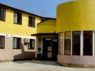 二階建ての建物は、上下階の外壁の色が違うツートンカラーの建物である。玄関右側の壁は、半円形にカーブしている。