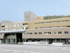 背後に山並みがある敷地に建っている４階建ての施設外観