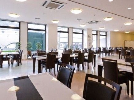 持ち手がついた大きな背もたれのある黒い椅子が置かれている食堂