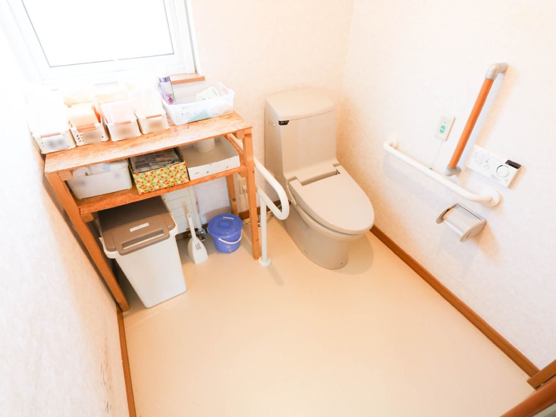 採光窓から陽の入る明るいトイレがある。広い空間になっており、便座の横には手すりが設けられている。壁にはナースコールもある。