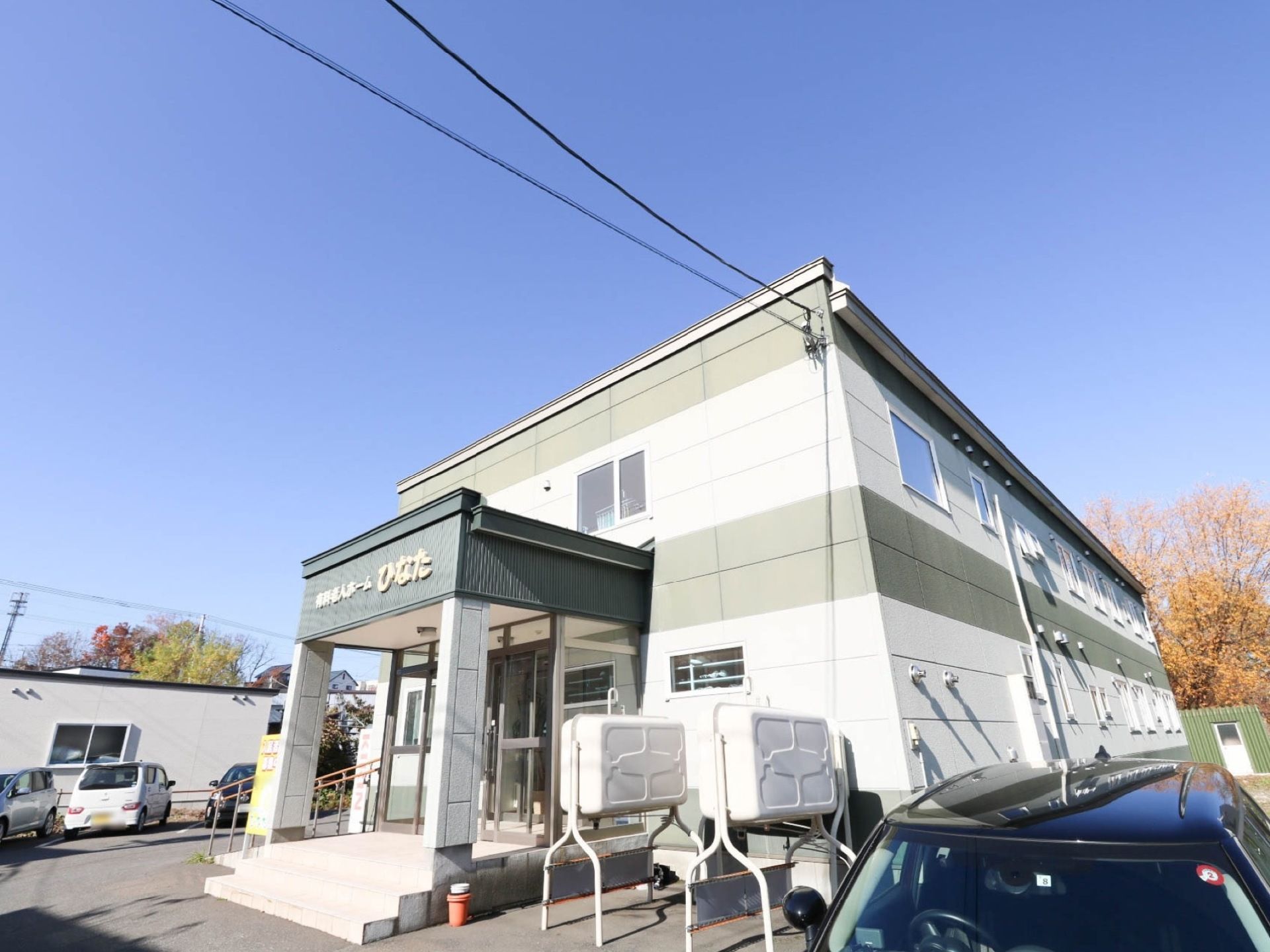 ２階建ての住宅があり、玄関前は階段になっている。階段の脇には手すりの付いたスロープが設けられている。