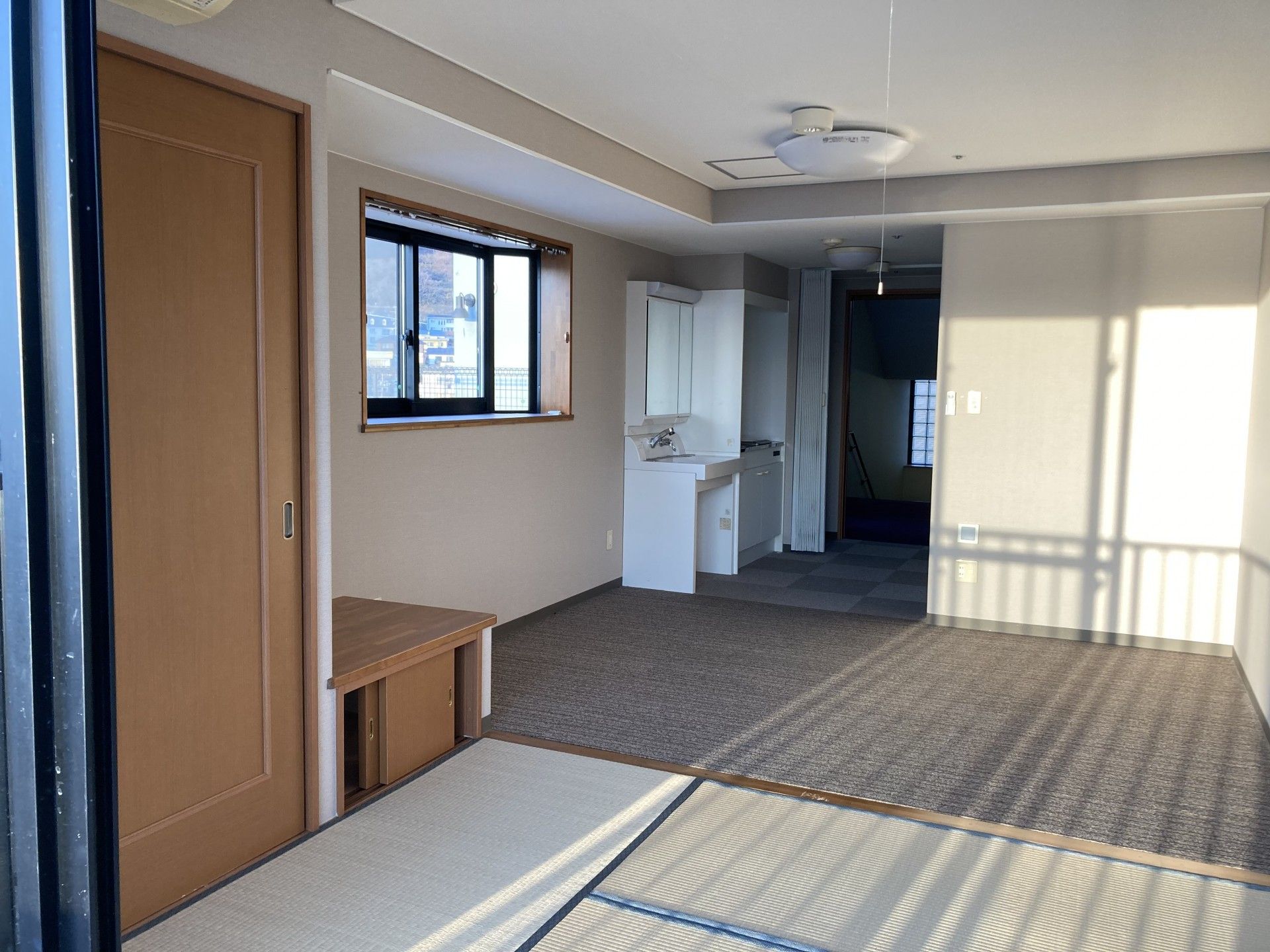 カーペットと畳が敷かれた居室では、足元が冷えにくく快適に過ごすことができる。白色の壁紙で明るい空間となっている。