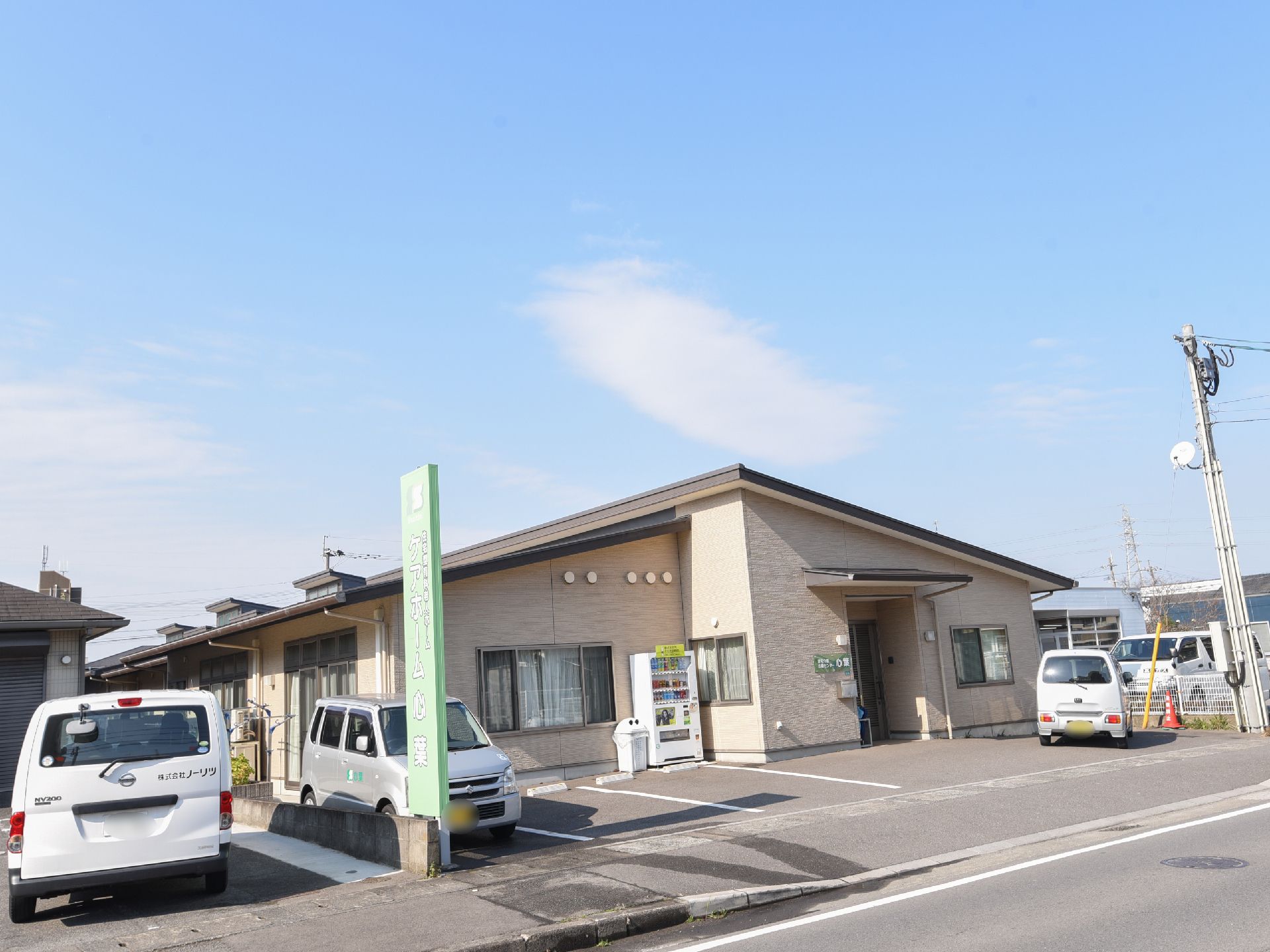 平屋建ての建物で、建物に沿って自動販売機が設置されている。施設前に駐車場が用意されており、車が数台停められている。