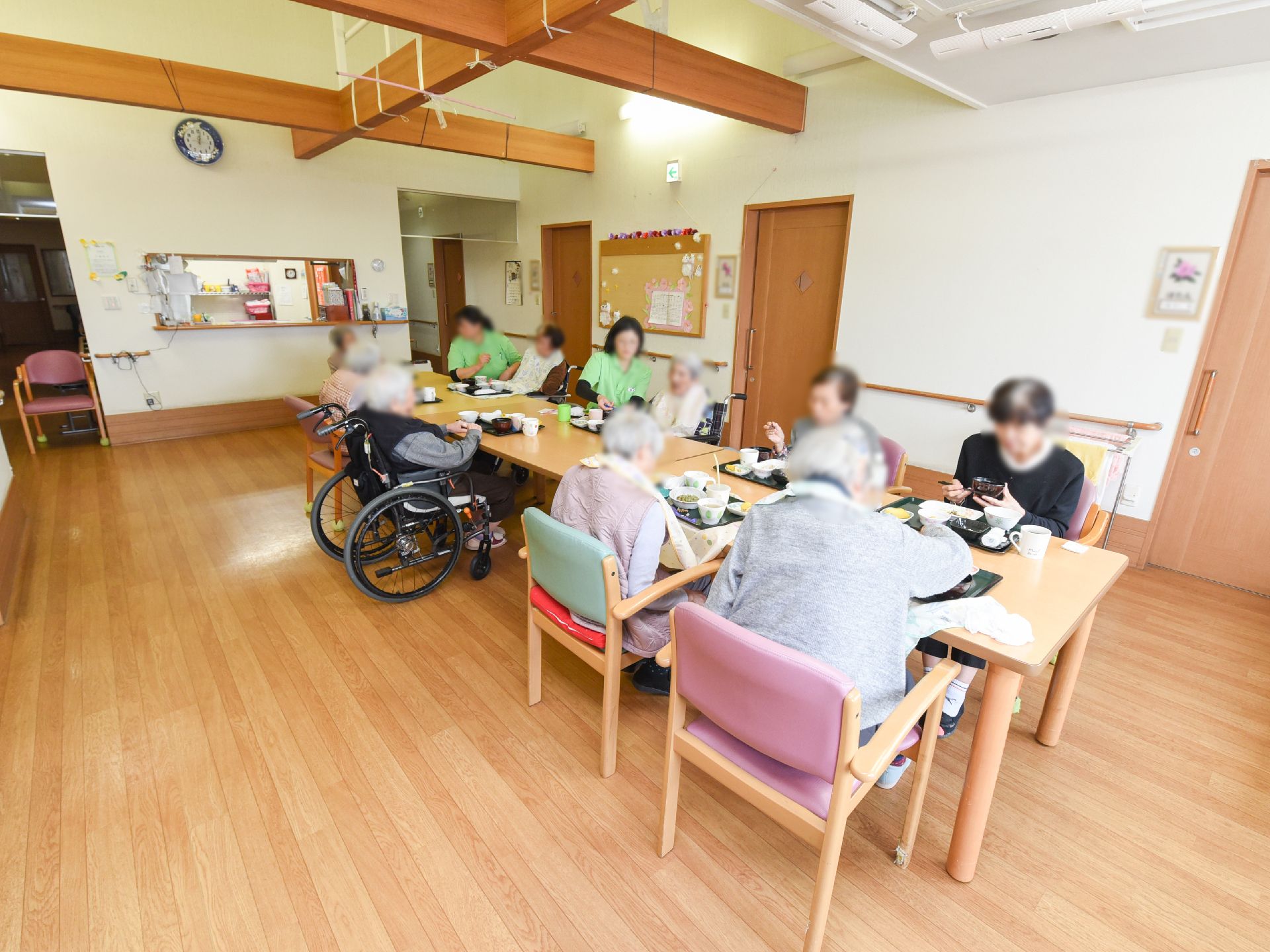 テーブルをつなげて置いている食堂でお食事を召し上がっている入居者様たち