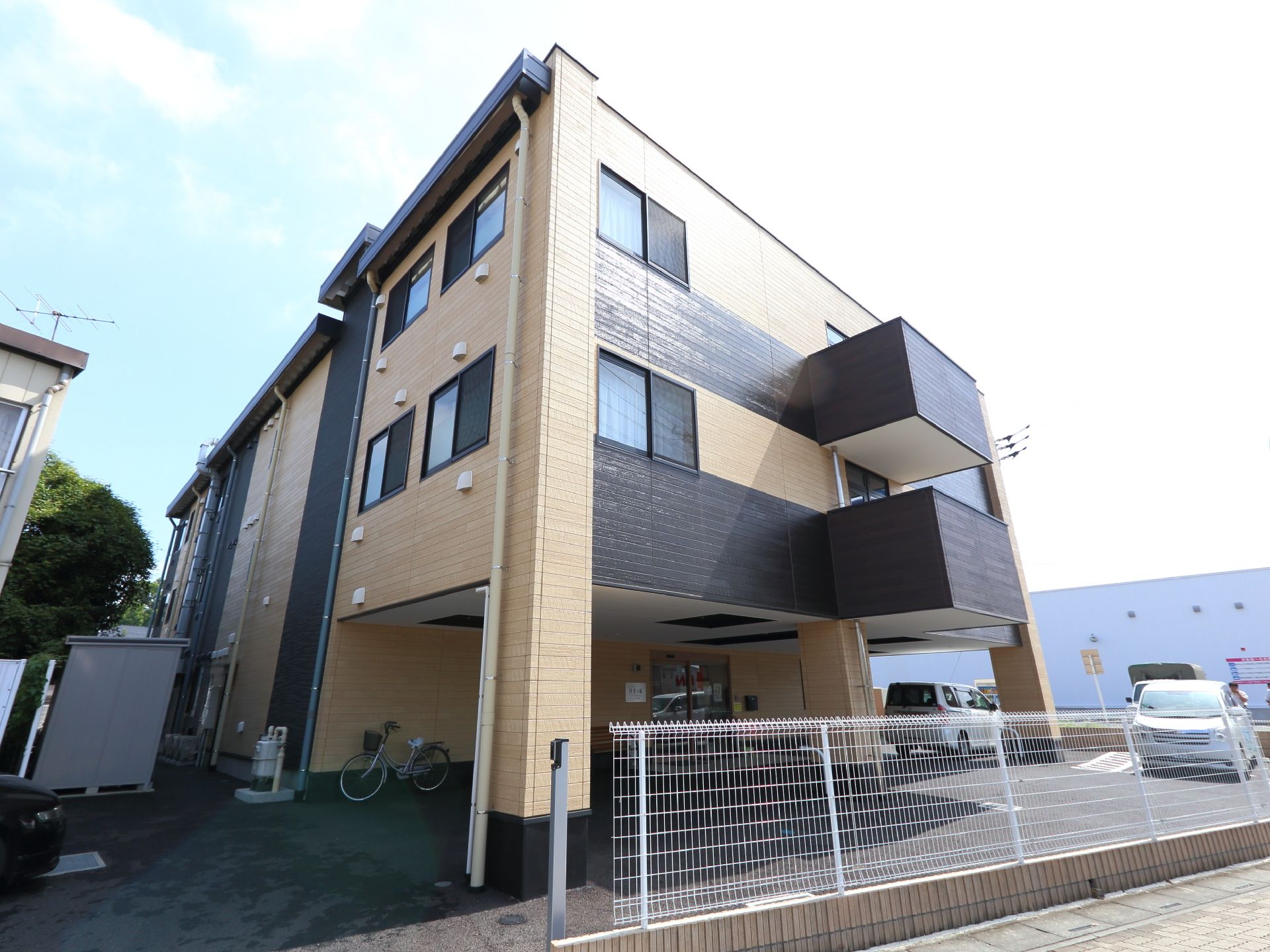 アパート的な外見を持つ施設の建物。外壁はカーキ色とダークブラウンで縞模様のようなものを形成している。