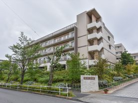 広々とした敷地内にはガーデンスペースがあり、木々が植えられている。また道路に面した場所には、施設名の看板が取り付けられている。