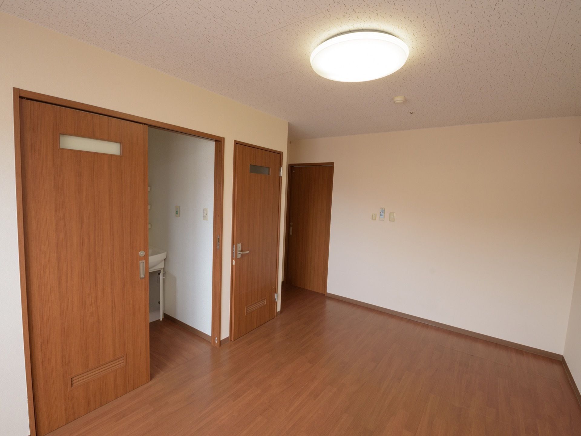 床がフローリングの居室。洗面スペースやトイレの入口はそれぞれ扉が付いていて、生活スペースと分かれている。